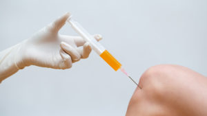 Doctor doing stem cell therapy on a patient knee