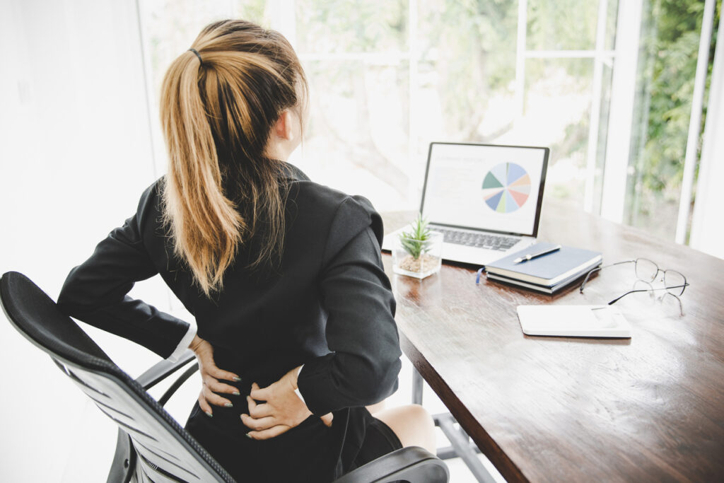 Young business woman at the office with terrible back pain