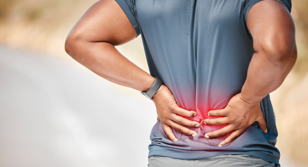 unrecognizable man standing alone outside and suffering from backache during his run