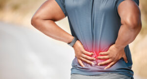 unrecognizable man standing alone outside and suffering from backache during his run