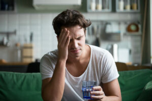 A young man is at home suffering from a headache.