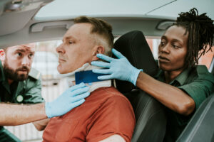 Paramedic placing a cervical collar to an injured man from car accident.