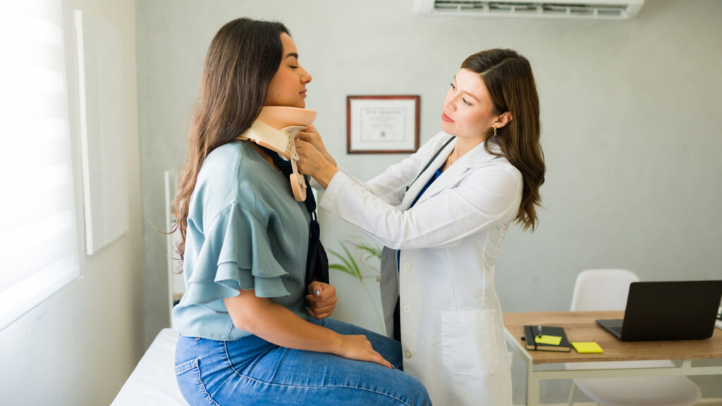 doctor is fitting a cervical collar on a female patient for whiplash