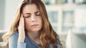 Young woman with migraine type of headache at home.